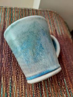 a blue and white cup sitting on top of a table next to a brown mat