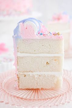 a slice of white cake with pink frosting and sprinkles on top