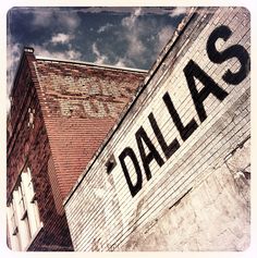 an old brick building with the word dalla painted on it's side and sky in the background