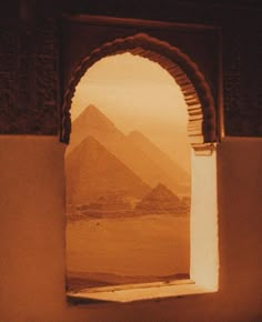 an arch opening into a desert with the pyramids in the background