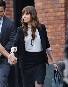 a woman in a black skirt and white shirt holding hands with a man in a suit