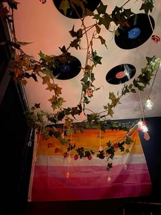 an array of vinyl records hanging from a ceiling with ivy growing on it and other record discs attached to the ceiling