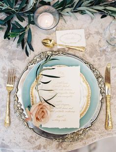 a table set with place settings and gold cutlery