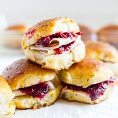 a stack of scones with cranberry sauce and cheese on them sitting on top of white paper