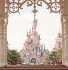 the entrance to disneyland's castle is seen through an archway in front of it