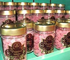 several jars filled with pink candy sitting on top of a shelf