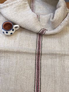 a cup of coffee sitting on top of a white sweater with a blue and red stripe