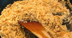 rice being cooked in a wok with a wooden spoon