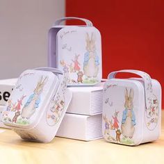 four tins with peter rabbit designs on them sitting on a table next to each other