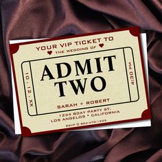 an admit two ticket sitting on top of a brown satin material covered tablecloth with hearts