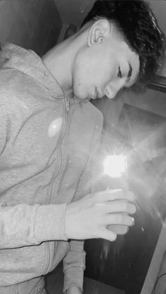 a young man holding a lighter in his right hand and looking down at the ground