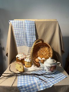 an assortment of pastries on a table next to a basket and teacups