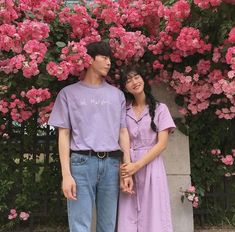 two people standing next to each other in front of pink flowers