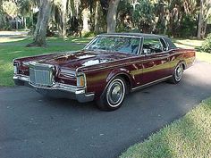 an old car is parked on the side of the road in front of some trees