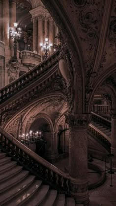 an ornate staircase with chandeliers and lights in a large, old building at night