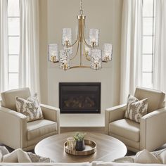 a living room filled with furniture and a chandelier hanging from the ceiling in front of a fire place