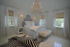 a white bedroom with zebra rugs and chandelier