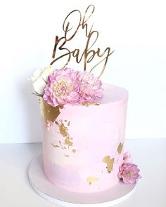 a pink cake with gold leaf and flowers on top that says oh bab baby