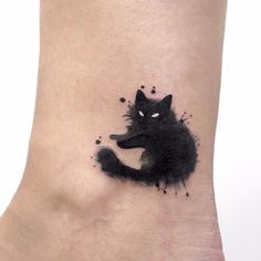 a black cat tattoo on the ankle with ink splatters all over it's body