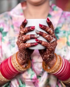 a woman holding up her hands with henna on it's palms and red nails