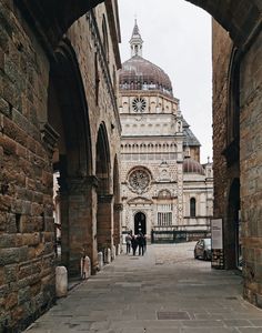 two people are walking through an archway in front of a building