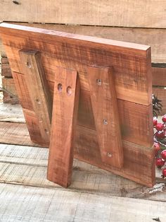 a wooden frame sitting on top of a wooden floor next to some flowers and berries