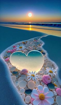 the sun is setting over the beach with flowers and hearts on it's sand