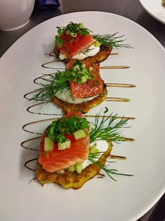 four appetizers are arranged on a white plate with garnishes and herbs