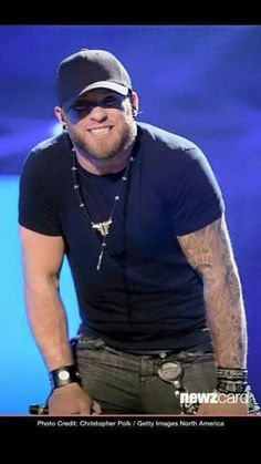 a man wearing a black hat and sunglasses on top of a stage with his hands in his pockets