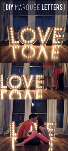 two people sitting on the floor in front of letters that spell love and are lit up with