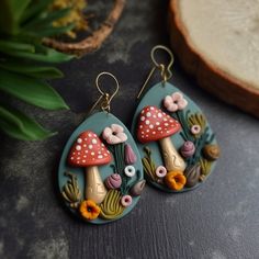 a pair of earrings with mushrooms and flowers on them