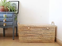 a wicker basket next to a blue dresser with a potted plant on top