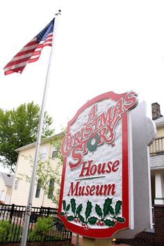 a sign for the christmas story house museum with an american flag flying in the background