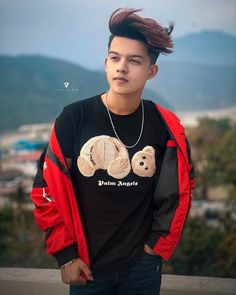 a young man standing on top of a roof next to a mountain with mountains in the background