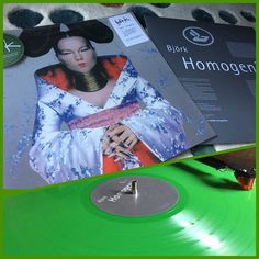 a green vinyl record with an image of a geisha woman on it and two other records