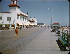 people are walking on the boardwalk next to buildings