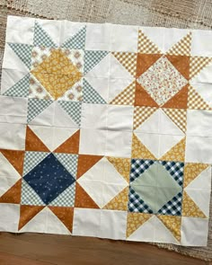 an orange, white and blue quilt is laying on the floor