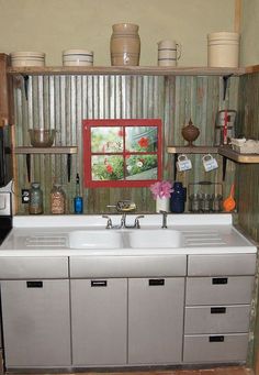 a kitchen with an old fashioned sink and shelves on the wall above it is full of pots and pans