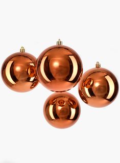 four shiny copper christmas ornaments against a white background