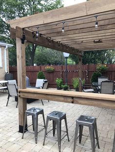 an outdoor bar with stools and tables in the middle of a backyard patio area