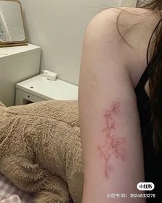 a woman with a tattoo on her arm is laying in bed next to a teddy bear