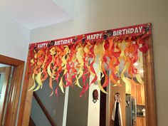 a birthday banner with streamers hanging from it's side in front of a mirror