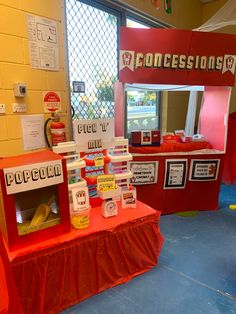 a red table topped with lots of items next to a sign that says concessionism