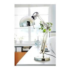 a desk lamp sitting on top of a white table next to a window with a potted plant