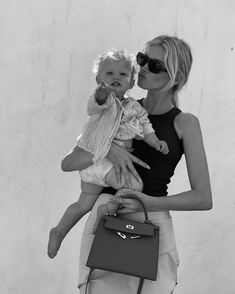 a woman holding a baby in her arms and a handbag on the other side