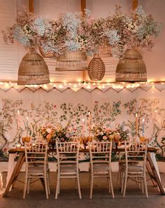 a dining room table with flowers and candles on the top, surrounded by wicker baskets