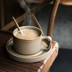 a cup of coffee sitting on top of a saucer next to a wooden chair