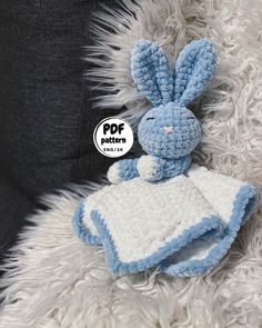 a crocheted blue and white stuffed animal sitting on top of a fluffy blanket