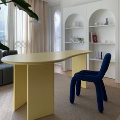 a blue chair sitting in front of a table next to a book shelf filled with books