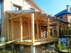 a house being built with wooden framing on the front and side of it, next to a brick building